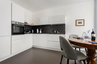 a kitchen with white cabinets and a table with chairs at Heart Apartment in Merano
