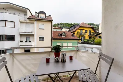 a white table and chairs on a balcony with buildings at Heart Apartment in Merano