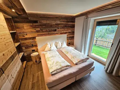a bed in a room with a wooden wall at Ciasa Sotiac in Antermoia