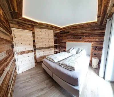 a bedroom with wooden walls and a bed in a room at Ciasa Sotiac in Antermoia
