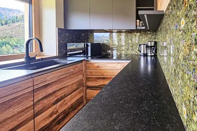 a kitchen with wooden cabinets and a black counter top at Ciasa Sotiac in Antermoia