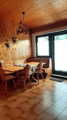 a dining room with a wooden table and chairs at Mansarda Villaggio Veronza in Carano