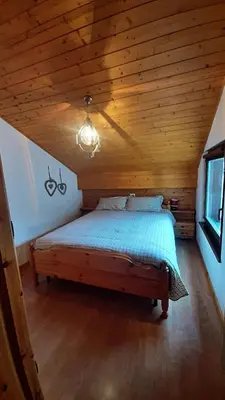 a bed in a room with a wooden ceiling at Mansarda Villaggio Veronza in Carano
