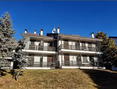 a large white building on top of a hill at Mansarda Villaggio Veronza in Carano