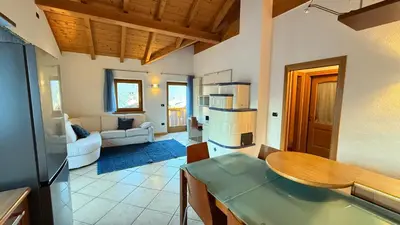 a living room with a table and a kitchen at Appartamento Villa Nicole in Transacqua
