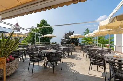 an outdoor patio with tables and chairs and umbrellas at Alea Living in Tirolo