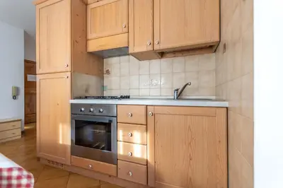 a kitchen with wooden cabinets and a stainless steel oven at Casa Falcade in Falcade