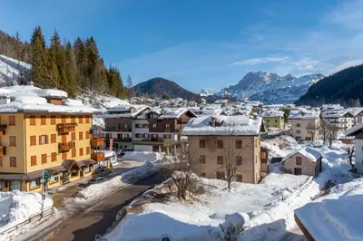 a town covered in snow with mountains in the background at Casa Falcade in Falcade