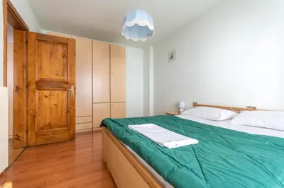 a bedroom with a bed with a green blanket at Casa Falcade in Falcade