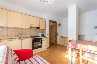 a kitchen with wooden cabinets and a table with a red chair at Casa Falcade in Falcade