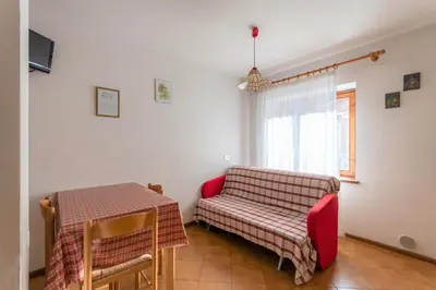 a living room with a table and a red couch at Casa Falcade in Falcade