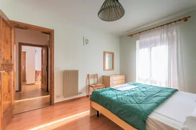 a bedroom with a bed and a window and a chair at Casa Falcade in Falcade