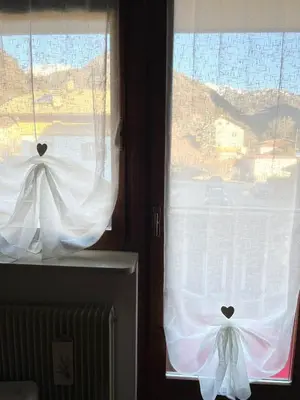 two windows with white curtains in a room at Appartamento Cuore delle Dolomiti in Cencenighe