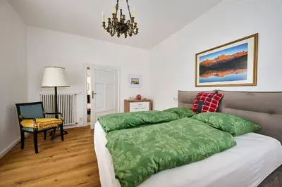a bedroom with a bed with green sheets and a chandelier at Villa Donata - Luxuriöses & großzügiges Apartment im Herzen von Kaltern, mit Innenhof, kostenlosem Parkplatz direkt am Haus in Caldaro