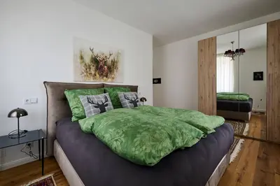 a bedroom with a bed with a green comforter at Villa Donata - Luxuriöses & großzügiges Apartment im Herzen von Kaltern, mit Innenhof, kostenlosem Parkplatz direkt am Haus in Caldaro