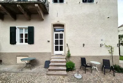 a white house with stairs and a table and chairs at Villa Donata - Luxuriöses & großzügiges Apartment im Herzen von Kaltern, mit Innenhof, kostenlosem Parkplatz direkt am Haus in Caldaro
