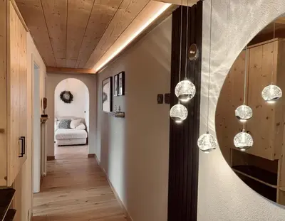 a hallway with pendant lights and a bedroom at Snowflake Apartment in Moena