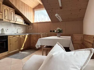 a kitchen with a table and chairs in a room at Snowflake Apartment in Moena