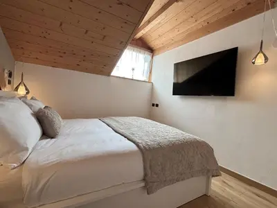 a bedroom with a bed and a flat screen tv at Snowflake Apartment in Moena