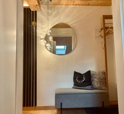 a mirror on a wall with a bench in a room at Snowflake Apartment in Moena