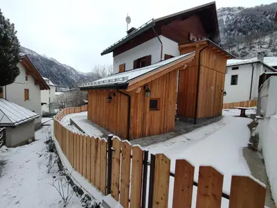a wooden building with a fence in the snow at Gianni Rocca Apartments APPARTAMENTO PIANO 1 E 2 in Rocca Pietore
