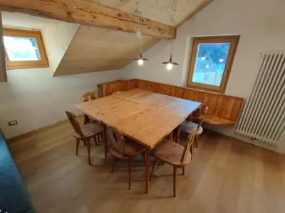 a room with a table and two windows and a radiator at Gianni Rocca Apartments APPARTAMENTO PIANO 1 E 2 in Rocca Pietore
