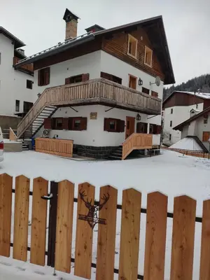 a house with a wooden fence in the snow at Gianni Rocca Apartments APPARTAMENTO PIANO 1 E 2 in Rocca Pietore