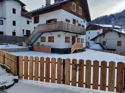 a house with a wooden fence in the snow at Gianni Rocca Apartments APPARTAMENTO PIANO 1 E 2 in Rocca Pietore