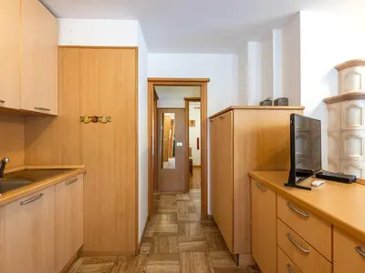 a kitchen with wooden cabinets and a flat screen tv at Apartment Fontanelle-4 by Interhome in Alba di Canazei