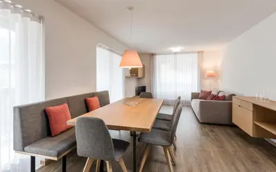 a dining room with a table and chairs and a couch at Moderne panorama Apartments in den Dolomiten, 2min von den Liften in Selva di Val Gardena
