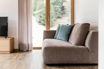 a couch in a living room with a large window at Moderne panorama Apartments in den Dolomiten, 2min von den Liften in Selva di Val Gardena