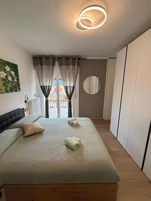a bedroom with a large bed and a large window at Casa GOLLES - Val Di Fiemme in Castello di Fiemme