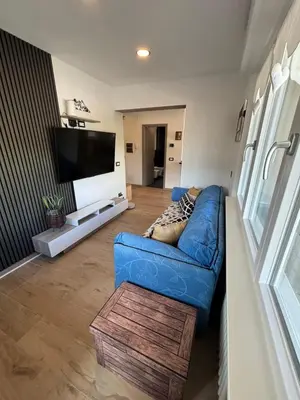 a living room with a blue couch and a flat screen tv at Casa GOLLES - Val Di Fiemme in Castello di Fiemme