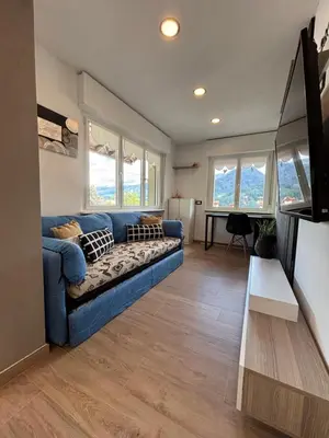 a living room with a blue couch and windows at Casa GOLLES - Val Di Fiemme in Castello di Fiemme