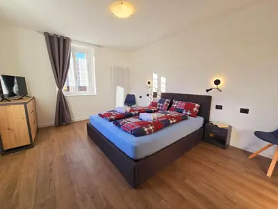 a bedroom with a large bed and a television at Casetta sui Monti - Alpine Stay Apartments in Tesero