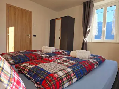two beds in a bedroom with a plaid blanket at Casetta sui Monti - Alpine Stay Apartments in Tesero