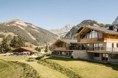 two people standing in the snow in front of a house at Muliné Lodge in Selva di Val Gardena