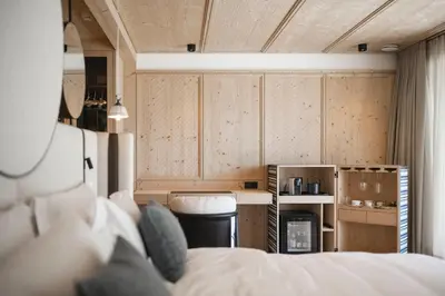 a room with a bed and a kitchen with wooden cabinets at Muliné Lodge in Selva di Val Gardena