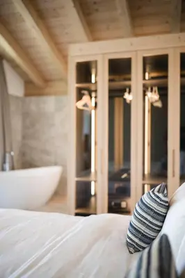 a bedroom with a white bed and a bath tub at Muliné Lodge in Selva di Val Gardena