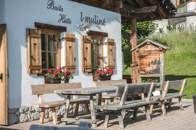 a picnic table and benches outside of a building at Muliné Lodge in Selva di Val Gardena