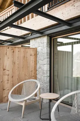 two chairs and a table on a patio at Muliné Lodge in Selva di Val Gardena