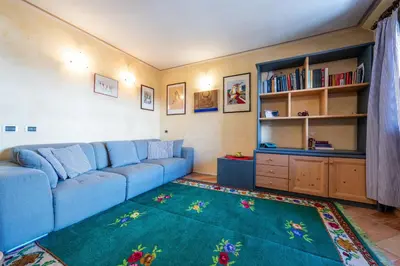a living room with a blue couch and a rug at Cesa Malvi in Canazei