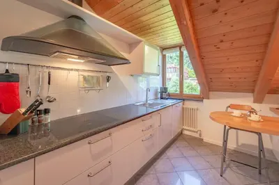 a kitchen with white cabinets and a wooden ceiling at Maison sous le ciel in Caldaro