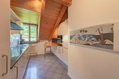 a kitchen with white walls and wooden ceilings at Maison sous le ciel in Caldaro