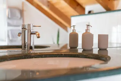 a bathroom sink with three soap bottles on a counter at Maison sous le ciel in Caldaro