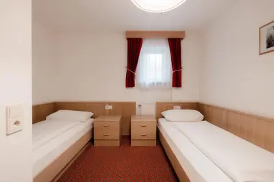 two beds in a small room with a window at Apartment Hotel Elvis in Ortisei