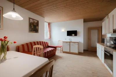 a kitchen and living room with a couch and a table at Apartment Hotel Elvis in Ortisei