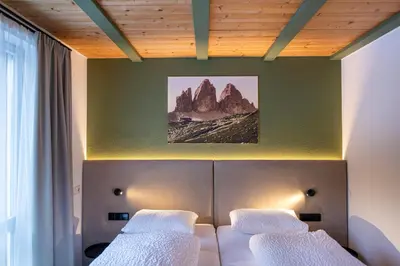 a bedroom with two beds and a wall with mountains at Residence Petlin Filip in Ortisei
