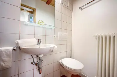 a white bathroom with a toilet and a sink at Residence Petlin Filip in Ortisei