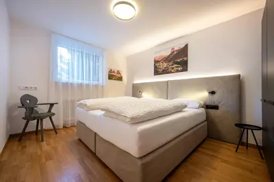 a bedroom with a large white bed and a window at Residence Petlin Robert in Ortisei